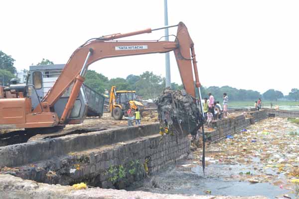 Churning out pollutants The JCB machine in action to clear the Futala waters of the filthy spread of nirmalya. 