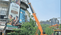 Woken up: NMC pulls down worn out hoarding atop building in Dharampeth